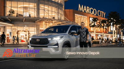 Supir Altranscar Rent Car siap melayani sewa Innova Depok dengan mobil silver di depan Margo City malam hari.